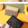 A close-up of an elegant PU leather card holder purse in black and brown tones resting on a wooden surface.