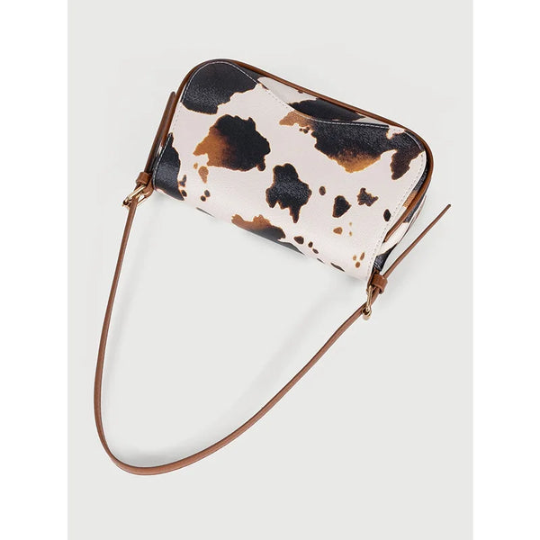 A single shoulder bag featuring a cow print pattern in beige and brown on a tan background.
