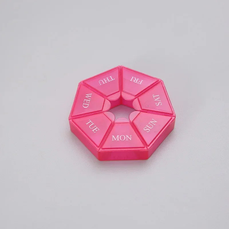 A pink weekly pill organizer divided into seven sections labeled with the days of the week.