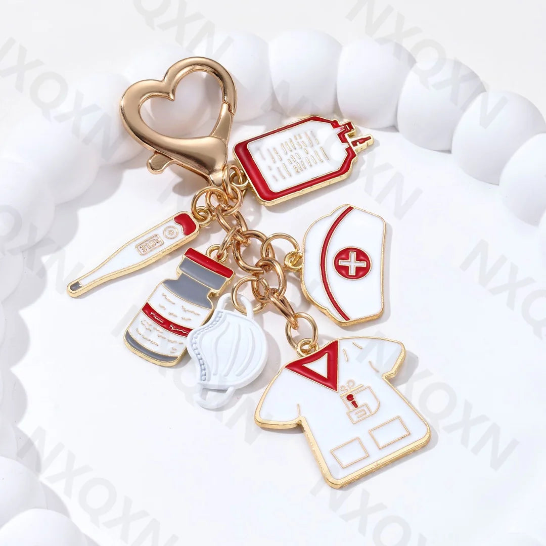 Gold-toned keychain featuring a heart charm and various medical-themed enamel pins like an infusion pump and thermometer