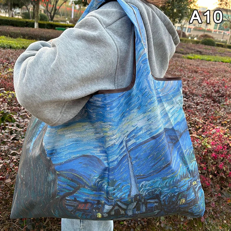 A person is carrying a large blue and white watercolor print shopping tote bag with a gray hoodie.