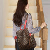 A woman wearing a brown leather backpack stands next to a wooden staircase.