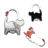Silver cat-shaped handbag hooks with a black silhouette and a sparkly white design