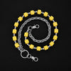 A silver chain necklace featuring yellow dice as charms, coiled in an oval shape.
