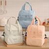 Una bolsa térmica reutilizable azul claro se muestra junto a una color crema sobre una superficie de madera.