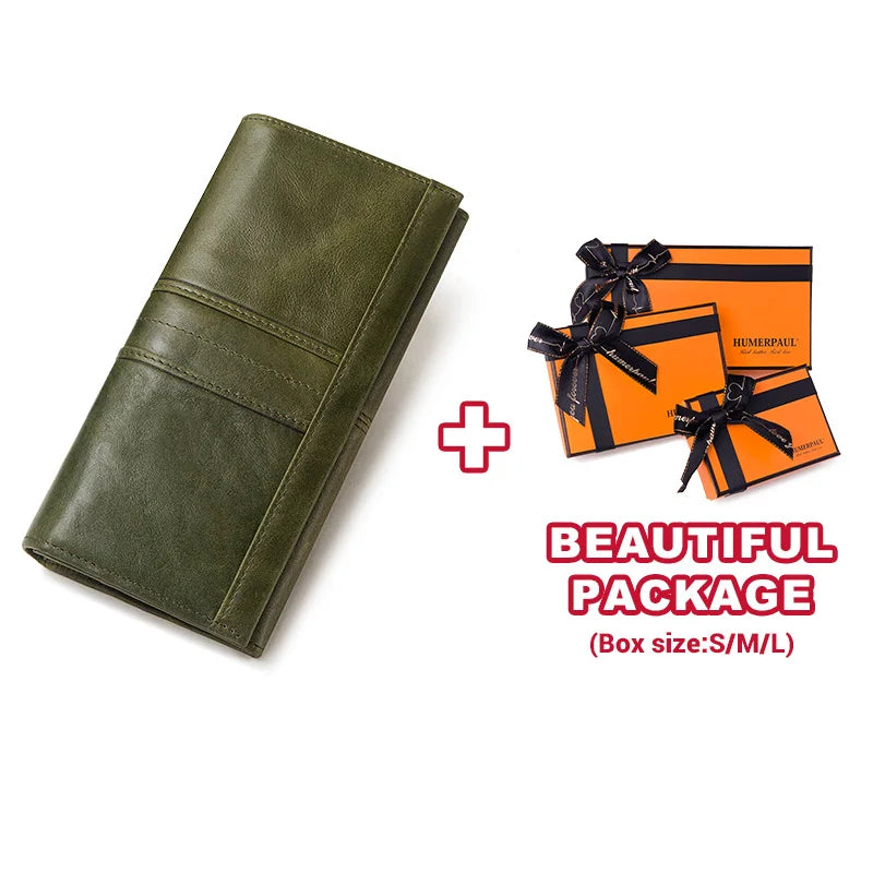 A dark olive green genuine leather clutch wallet next to two orange gift boxes.