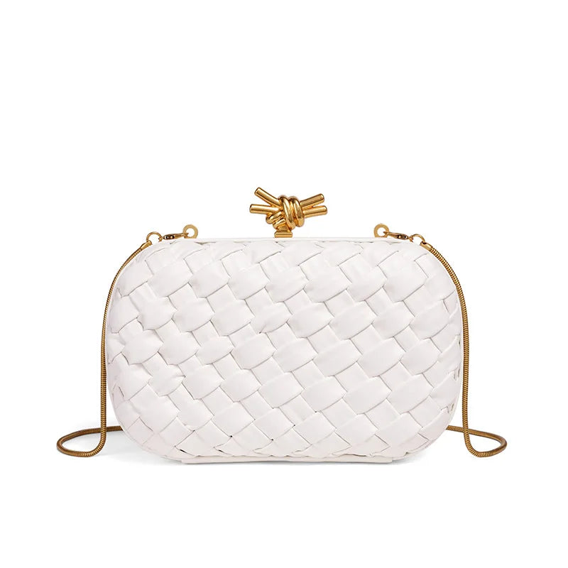 A white handwoven clutch evening bag with gold hardware is shown against a white background.