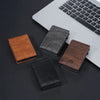 A collection of four men's PU leather card holder wallets in brown, black, and dark gray placed on a dark surface next to a l