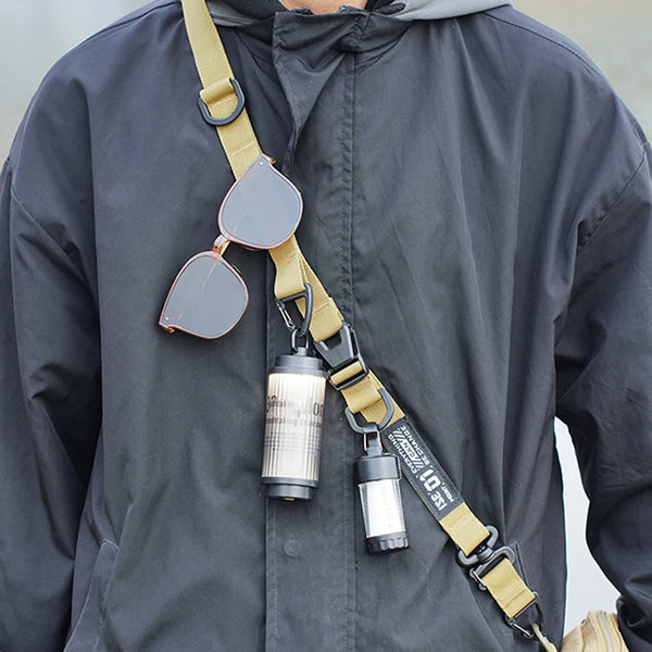 Eine Person trägt einen strapazierfähigen Outdoor-Camping-Crossbody-Gurt mit Sonnenbrille und Taschenlampe.