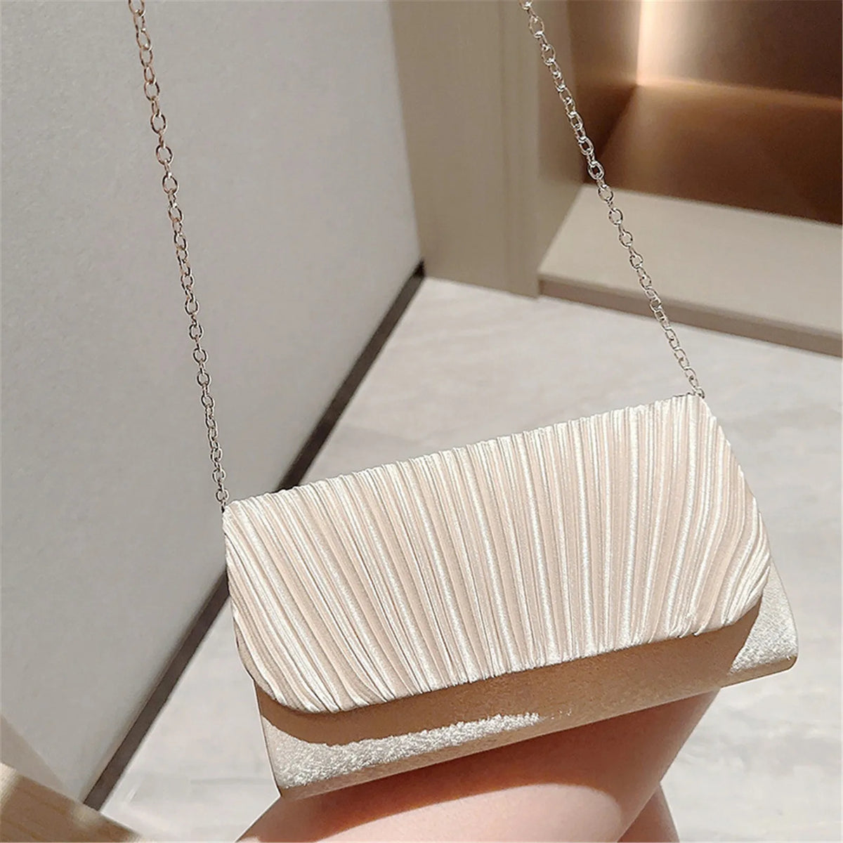 A luxury chain shoulder clutch bag in a pale beige color is displayed against a light background.