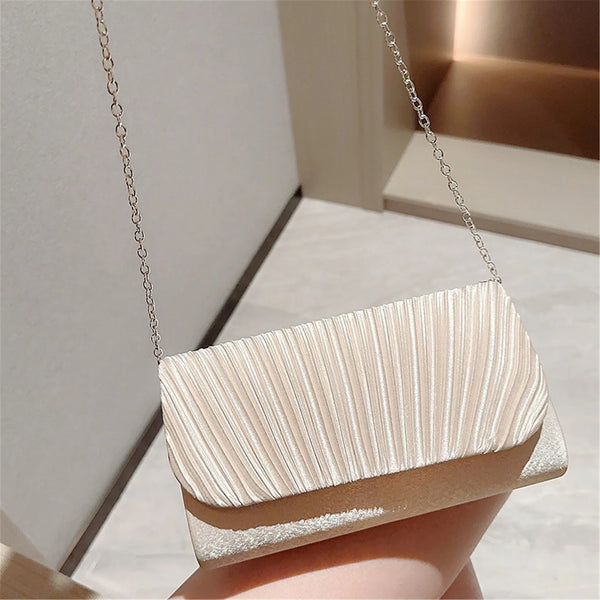 A luxury chain shoulder clutch bag in a pale beige color is displayed against a light background.
