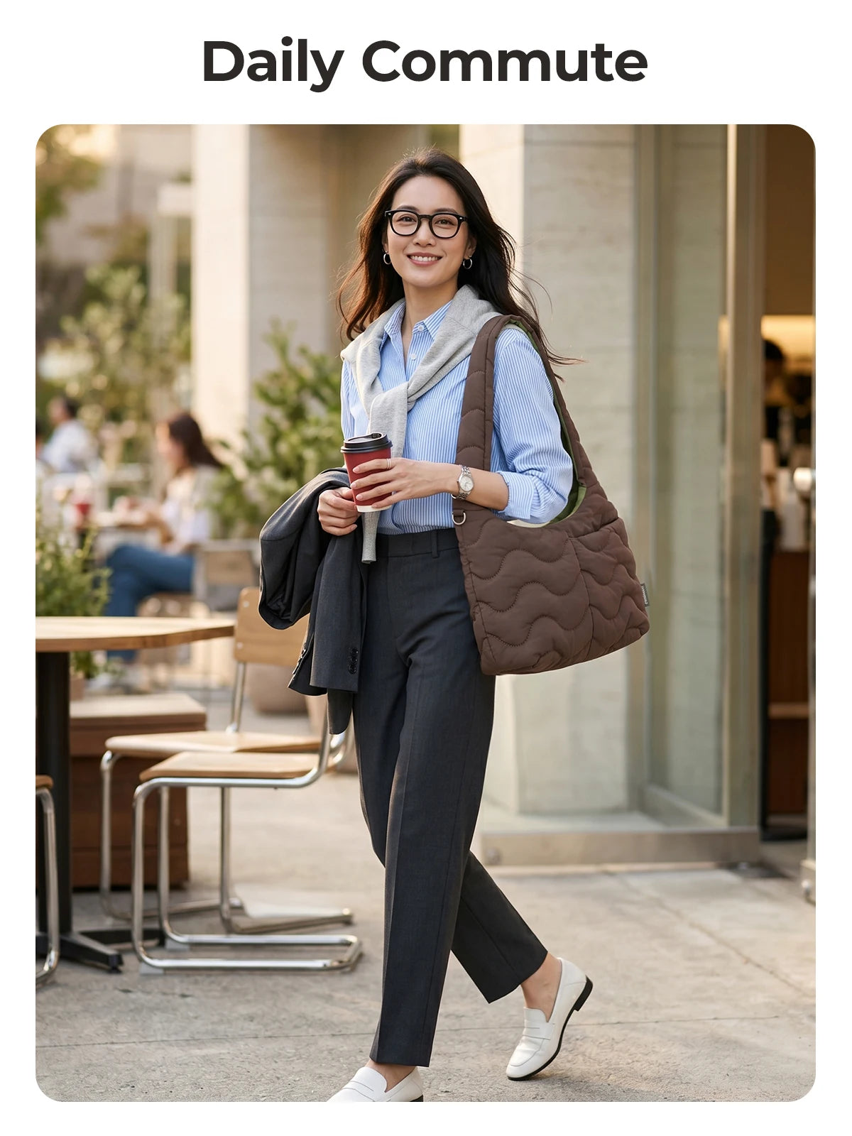 A woman wearing a blue shirt and dark pants carries a brown quilted nylon shoulder bag while walking outdoors.