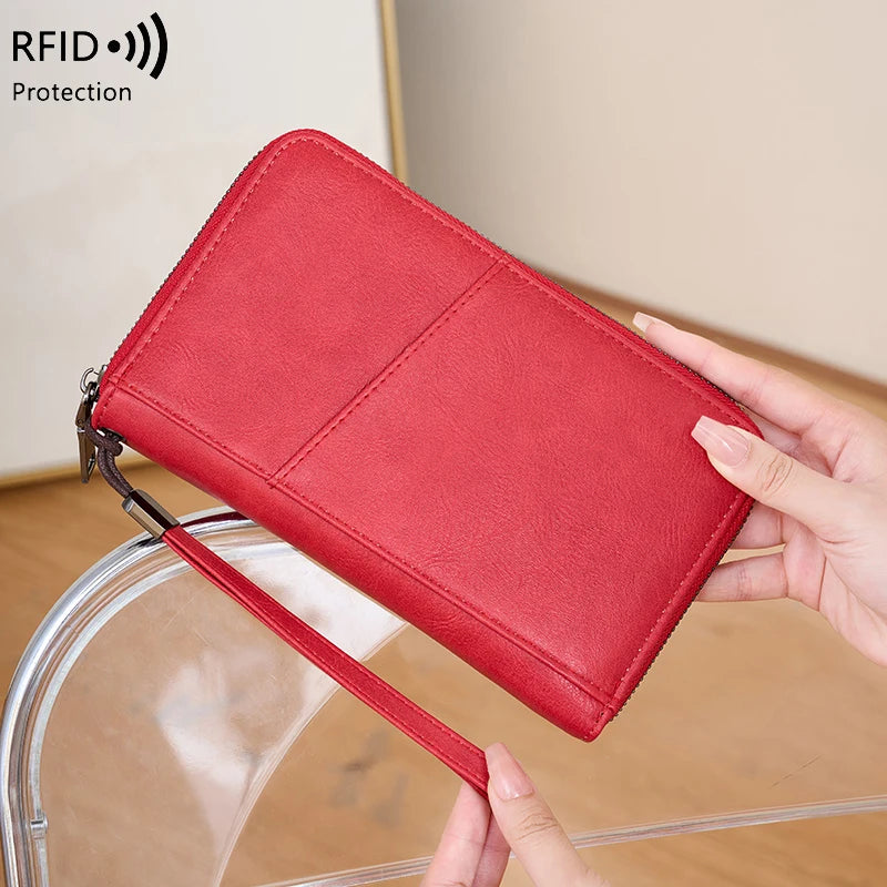 A red leather RFID blocking travel wallet is shown being held by a hand.