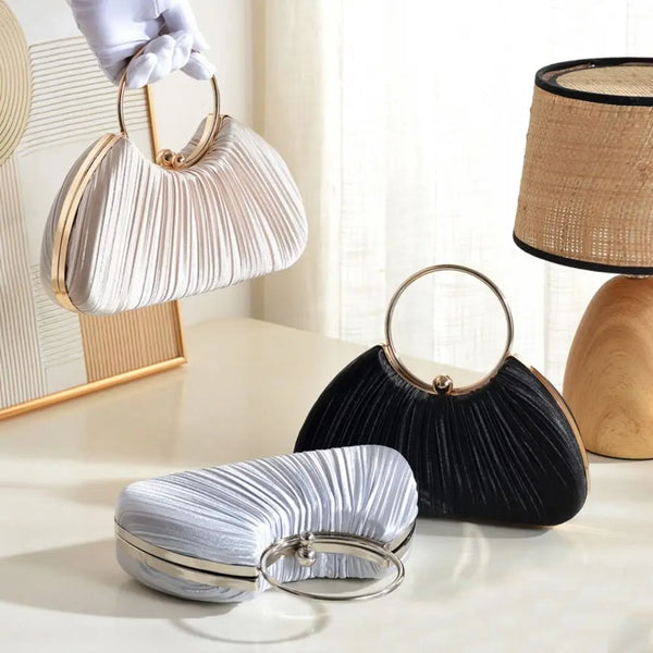 A set of elegant satin pleated evening clutch bags in silver and black, displayed on a light surface.