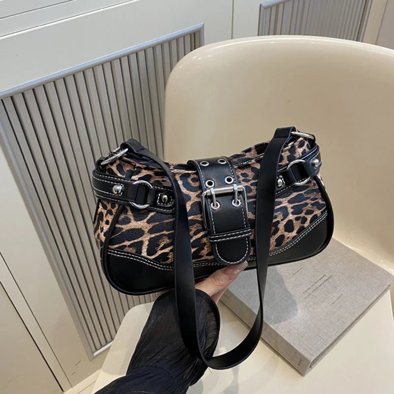 Un sac à main en similicuir à imprimé léopard noir tenu par une main sur un fond clair.