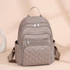 A light beige waterproof women's travel backpack with a quilted design and silver zippers.