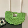A bright lime green rattan half-moon beach handbag hanging on a white wall.