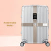 A silver-colored suitcase with a khaki cross strap and bundling belt is shown against a light pink background.