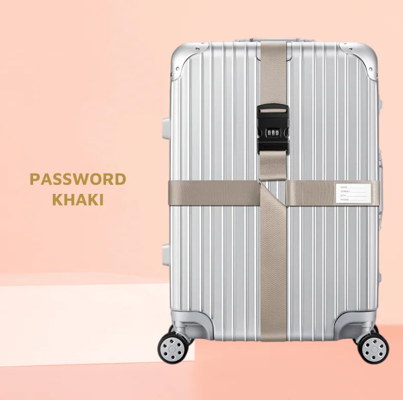 A silver-colored suitcase with a khaki cross strap and bundling belt is shown against a light pink background.