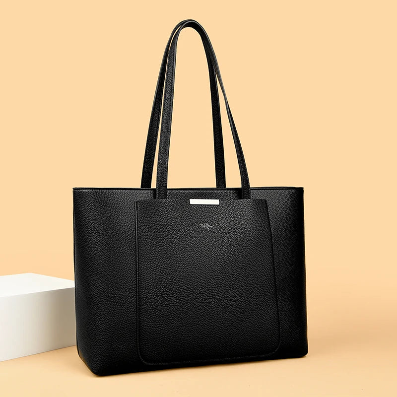 A black leather shoulder bag with long handles is displayed on a light beige background.