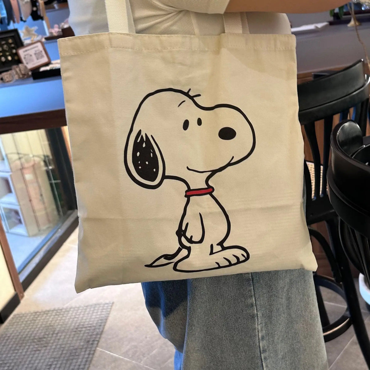 A white canvas shoulder bag featuring a black line drawing of a dog's head.