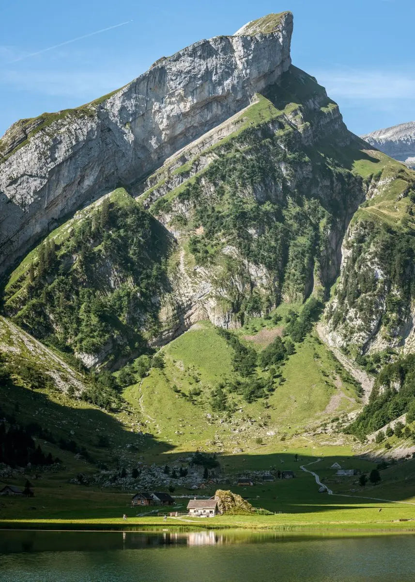 Landschaft mit steilen grünen Hängen und Wasser unter blauem Himmel