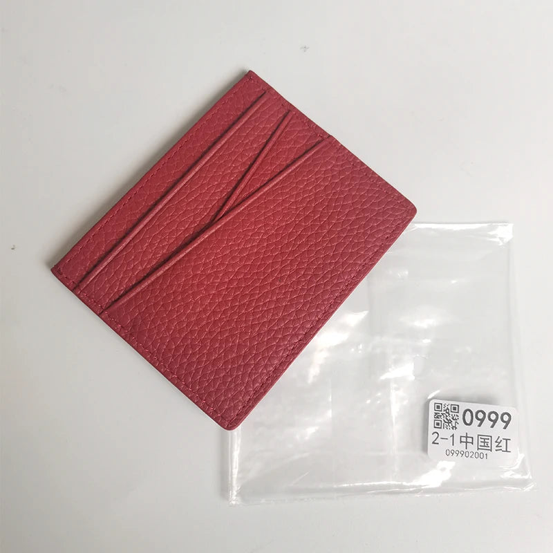 Porte-cartes en cuir véritable rouge-rose texturé dans une pochette plastique transparente.