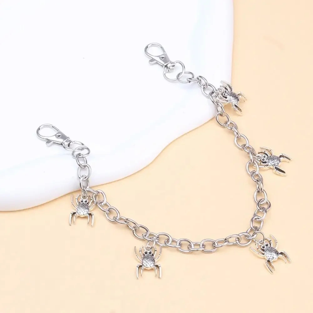 Silver metal purse chain strap with charm detailing laid out on a light background.