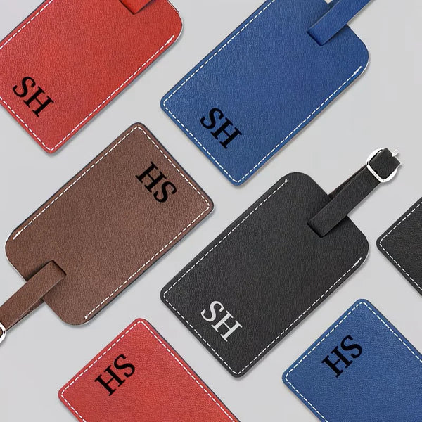 A set of personalized faux leather passport and luggage tags in red, blue, and black colors.