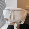 A white PU leather crossbody saddle bag with a woven chain strap is shown against a light background.