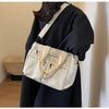 A woman is holding a cream and white striped textured corduroy tote bag with light beige adjustable straps.