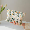 A hand holds a floral canvas makeup bag featuring green and orange flowers against a light background.