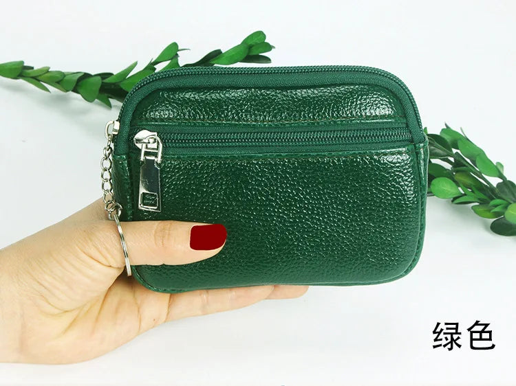 A hand holds a dark green compact PU leather mini wallet with a silver keychain.