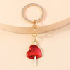 Gold-toned heart keychain with a red enamel pendant and a sun eye charm