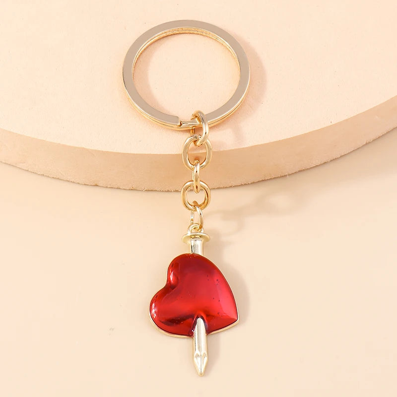 Gold-toned heart keychain with a red enamel pendant and a sun eye charm