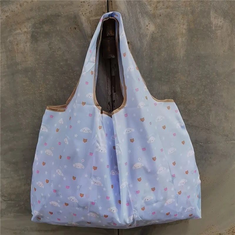 A light blue reusable shopping bag with a sheer fabric and small pink and white patterns is displayed against a concrete back
