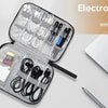 An open electronic organizer bag showing various cables and accessories next to a silver laptop.