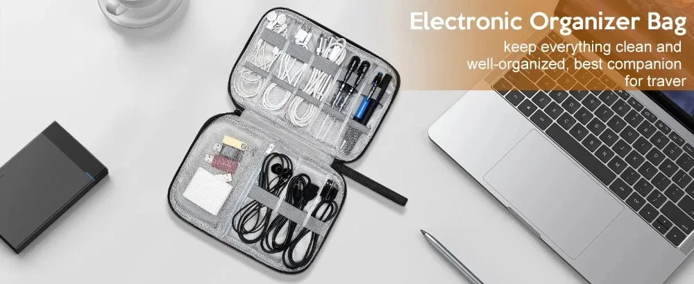 An open electronic organizer bag showing various cables and accessories next to a silver laptop.