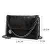 Black vintage flap crossbody bag with a silver chain strap shown from the side.