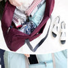 Un sac de voyage pliable marron ouvert, révélant des vêtements pliés et un smartphone à l'intérieur.