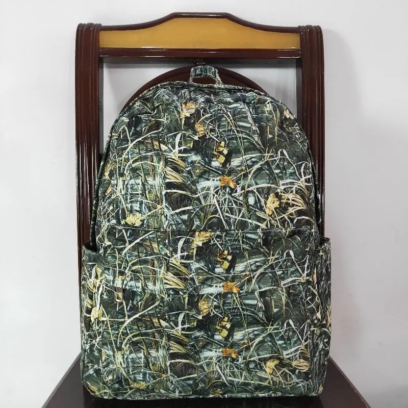 A dark green and black camouflage patterned toddler backpack displayed on a wooden hanger.