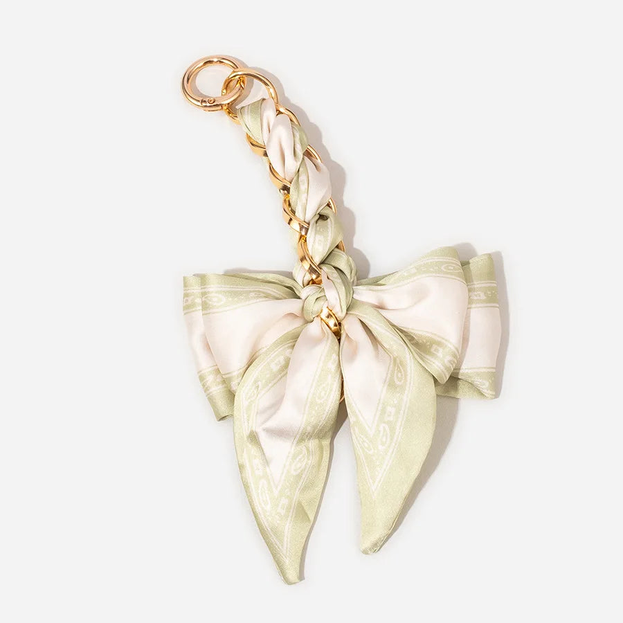 A beige satin adjustable bag strap with a gold-toned clasp and knot detail.