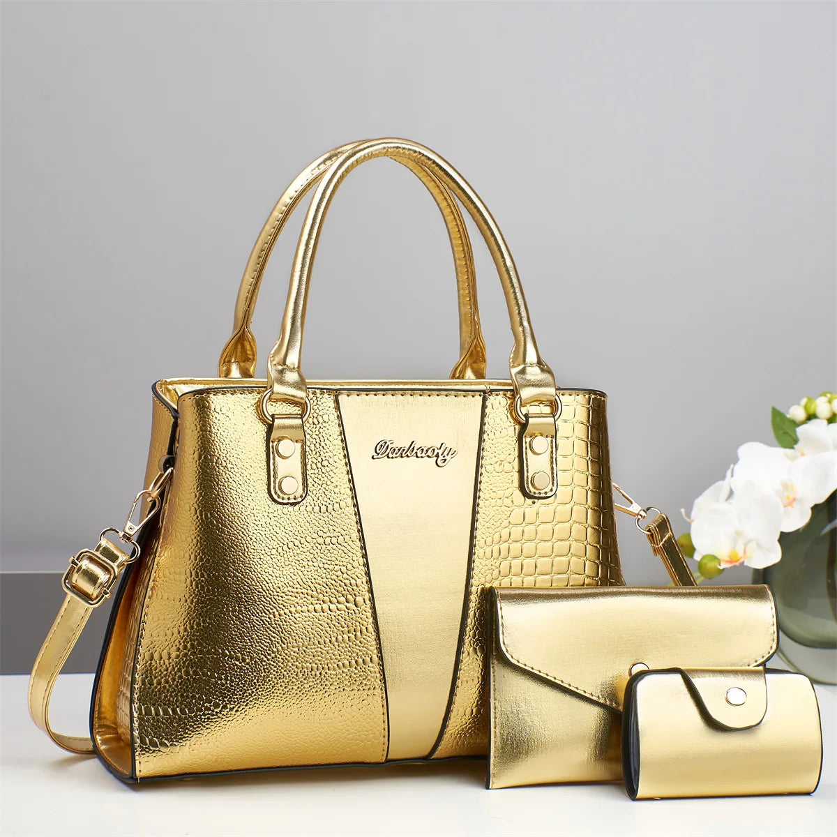 Set de bolso de piel de cocodrilo patentada dorada, incluye un bolso principal y un clutch.