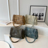 Colección de cuatro bolsos de cuero retro tipo cadena para hombros en marrón, verde oliva, gris oscuro y azul, mostrados sobr