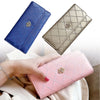 Three diamond quilted wallets in blue, gold, and pink are shown being held by a hand.