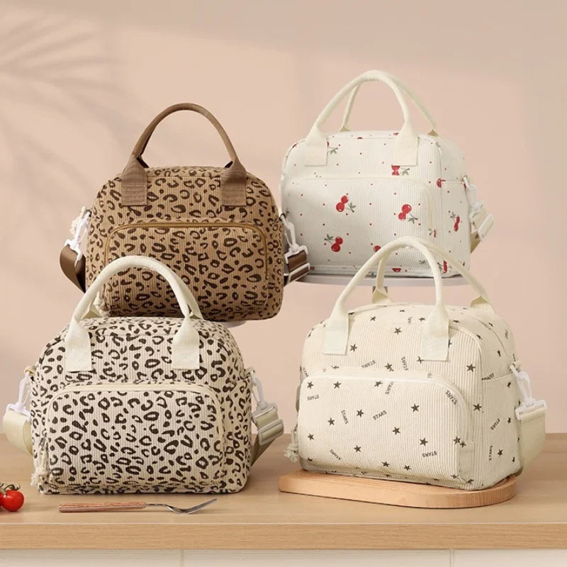 A set of three floral corduroy insulated lunch bags in beige and white patterns displayed on a wooden surface.