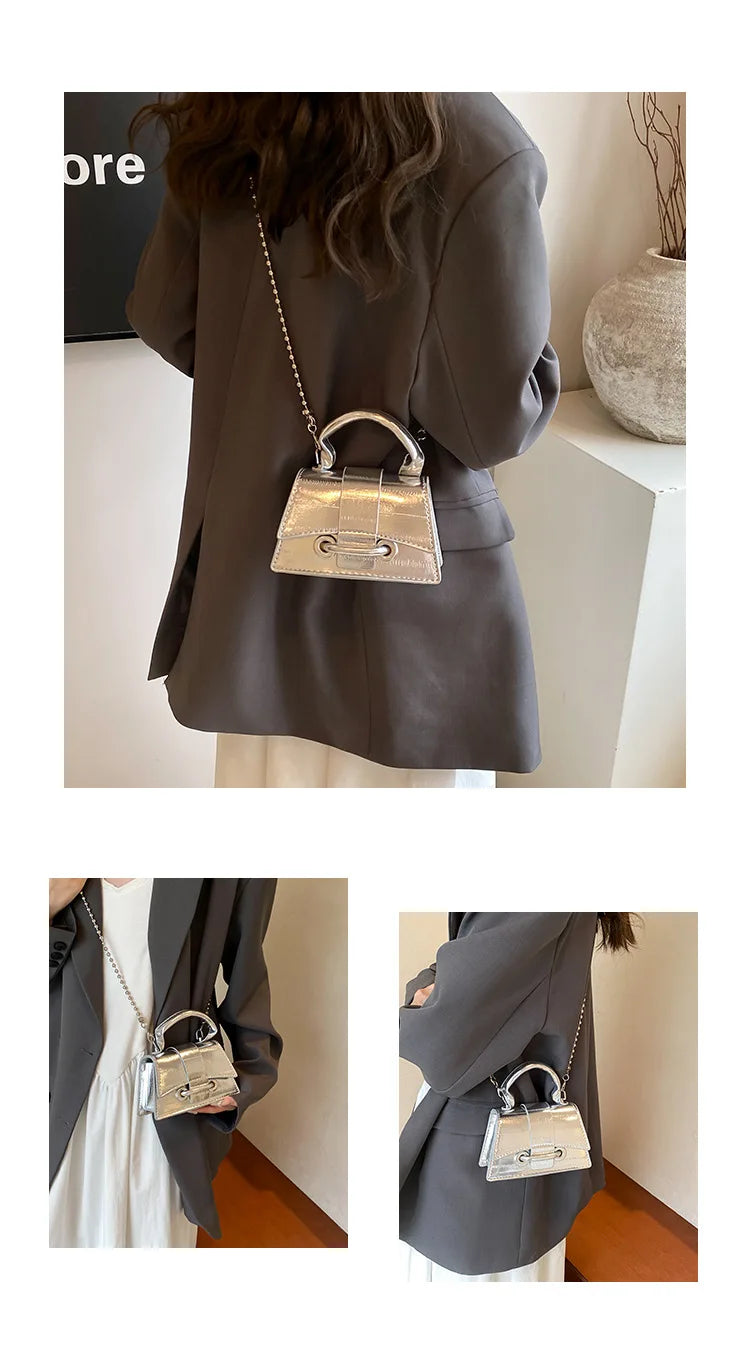 A close-up of a silver gold square crossbody bag with a chain strap worn by a woman in a gray blazer.