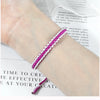 A close-up of a handmade braided rope bracelet with pink and white threads worn on a wrist.