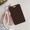 A dark brown card holder with a pattern of small blue stars is attached to a white braided lanyard.