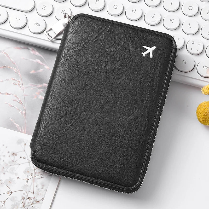 Black leather passport and document holder with a silver keychain on a white desk.